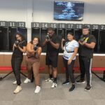 Five people stand in front of numbered lockers holding laser tag guns, posing for a group photo at a Florham Park arena, perfect for those seeking fun indoor summer activities.