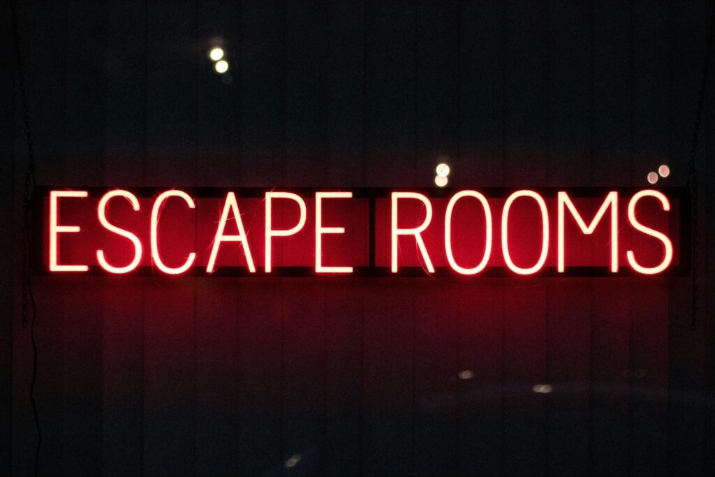 A neon sign with red letters reads "ESCAPE ROOMS" against a dark background—perfect for kids’ indoor fun or unique birthday party ideas in New Jersey.